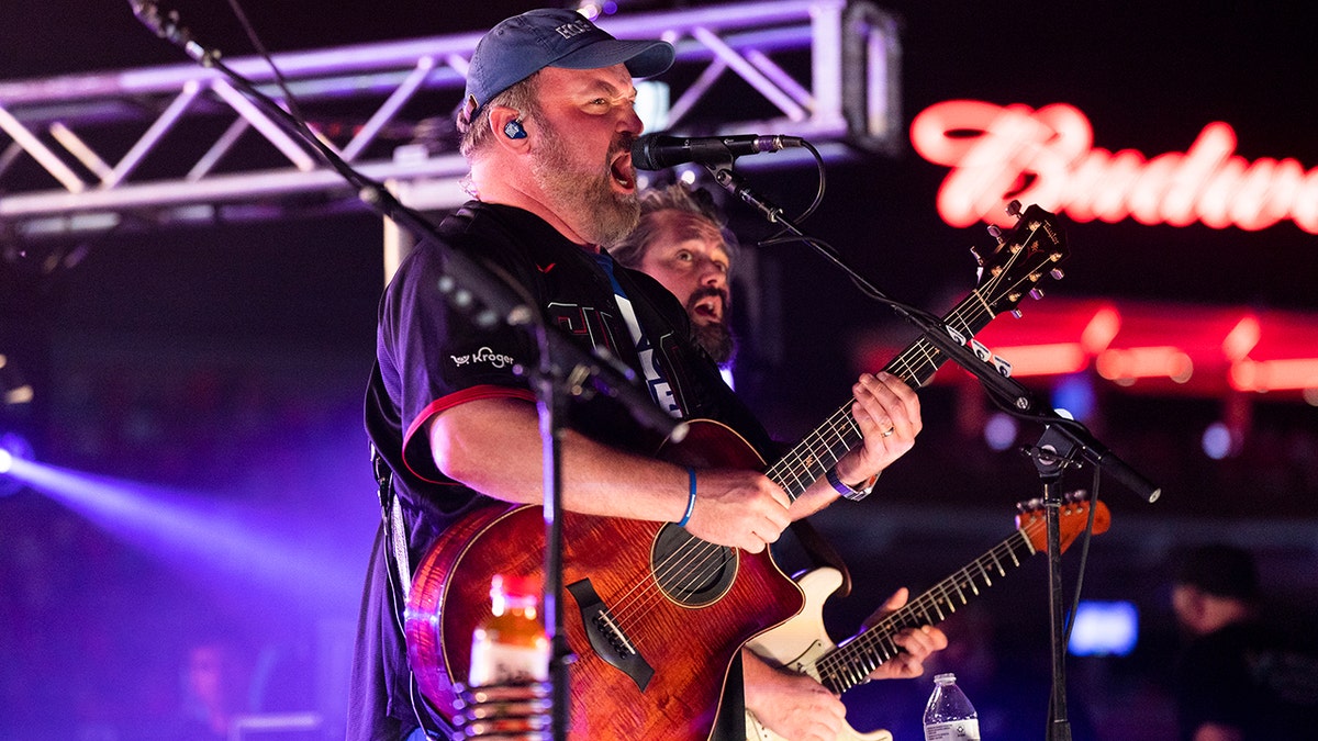 John Driskell Hopkins strums the guitar and sings on stage during Zac Brown Band concert