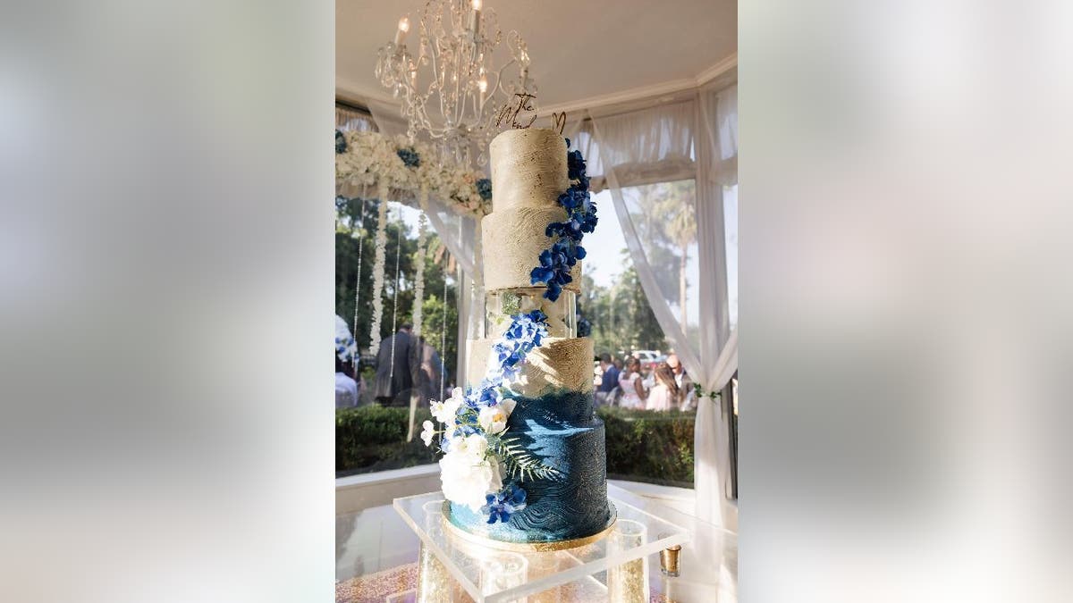 A blue and white wedding cake made by Lilly Mendoza sits on a cake table at a Florida hotel.