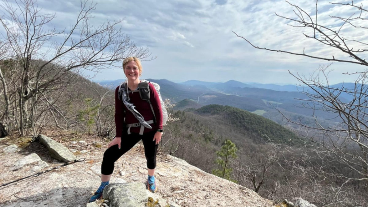 Melody Sasser poses at the top of mounting in hiking gear.