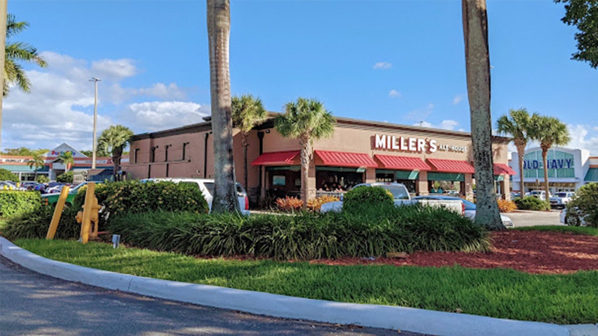 A single story restaurant flanked by palm trees.