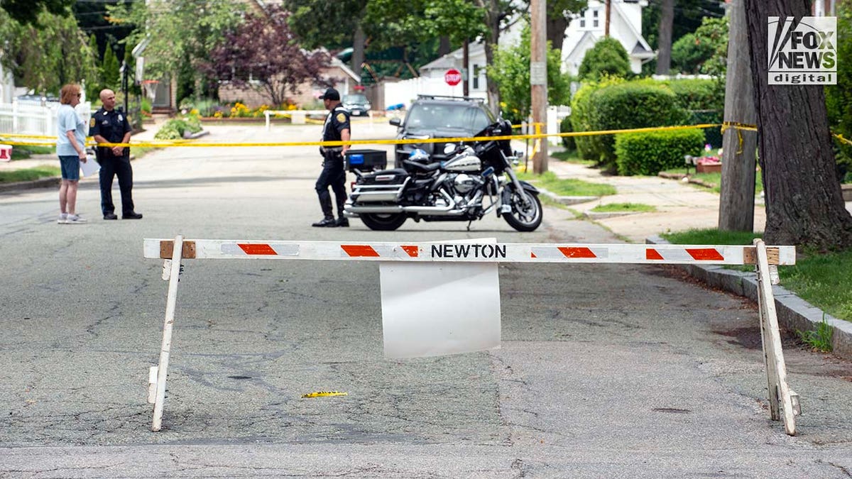 Police officers gather outside of the home where a triple homicide occurred in Newton, Massachusetts