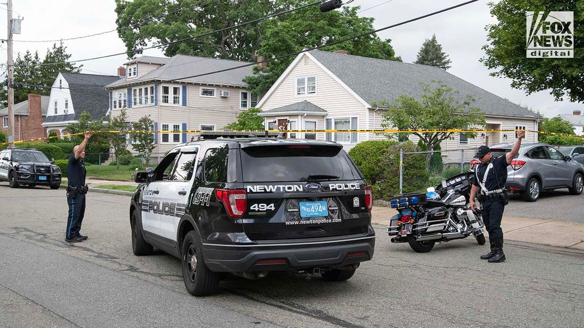 Police officers gather outside of the home where a triple homicide occurred in Newton, Massachusetts