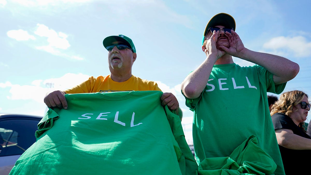 A's fans hold t-shirts that read "SELL"
