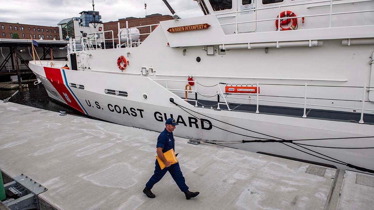 A member of the Coast Guard walks by a Coast Guard Cutter at the US Coast Guard Base Boston 