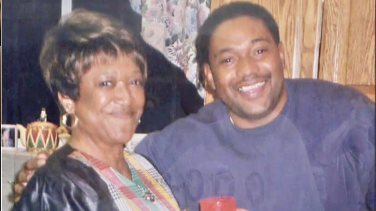 Minnie Smith smiling next to her son wearing a purple sweater