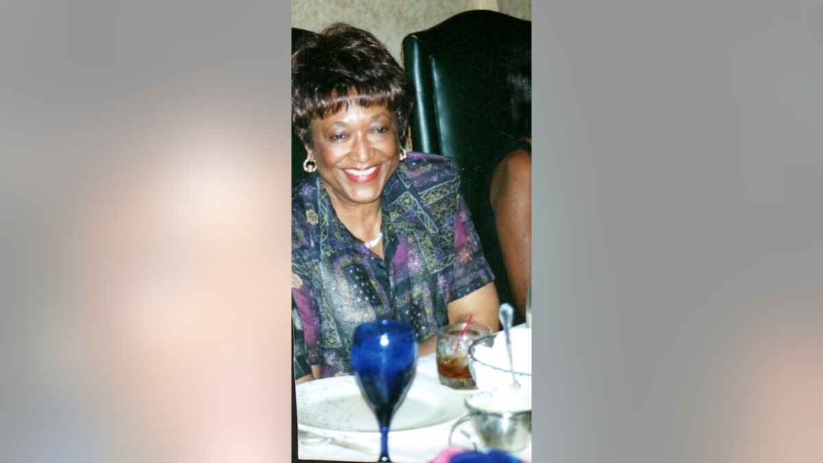 Minnie Smith wearing a multicolored blouse smiling at a dinner table