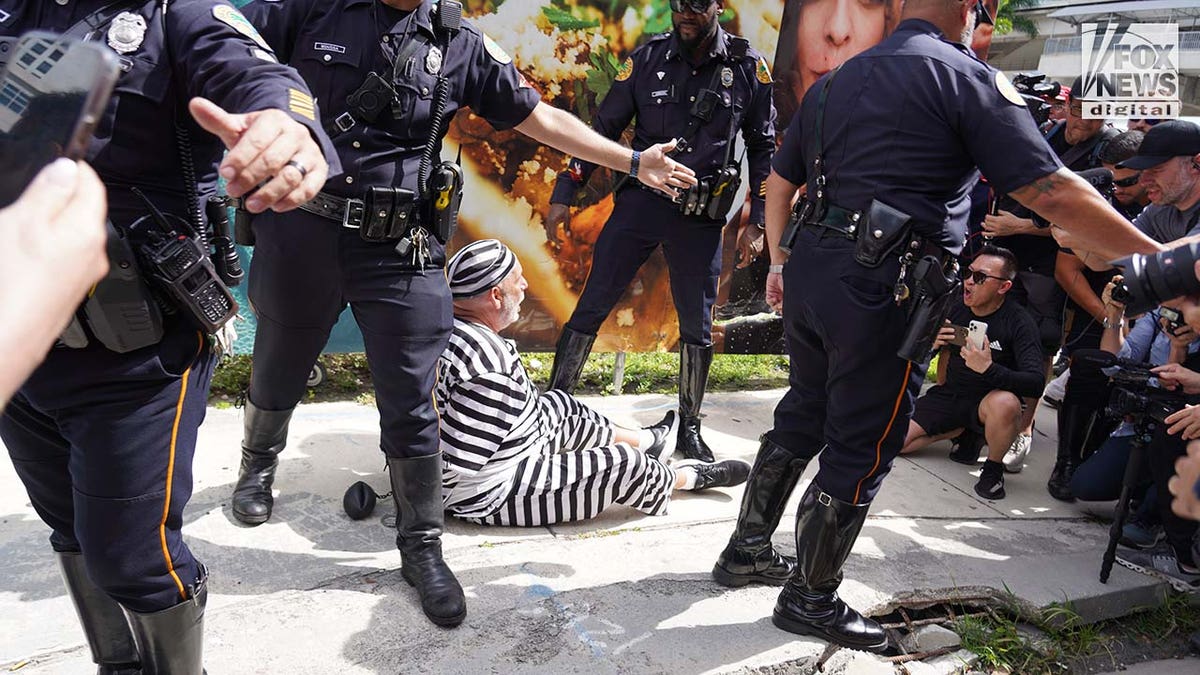A protestor is detained as former President Donald Trump’s motorcade departs the Wilkie D. Ferguson Jr. U.S. Courthouse in Miami, Florida on Tuesday, June 13, 2023.