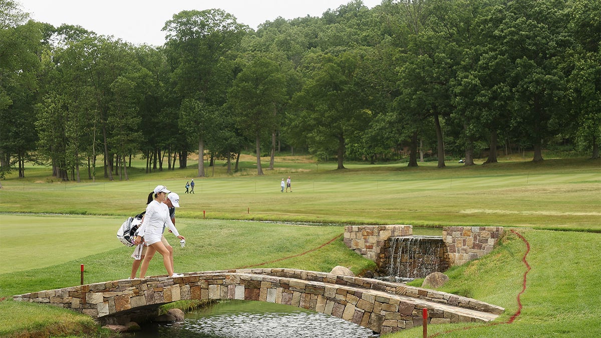 Rose Zhang walks over bridge with caddie