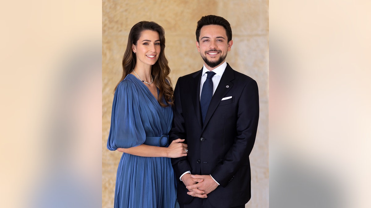 Princess Rajwa wearing a blue dress next to Crown Prince Hussein in a dark suit and blue tie