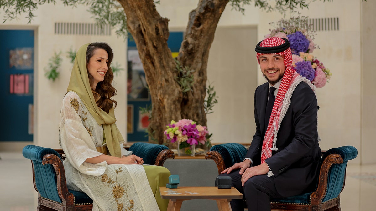 Princess Rajwa in a traditional beige and green dress next to Crown Prince Hussein in traditional regalia
