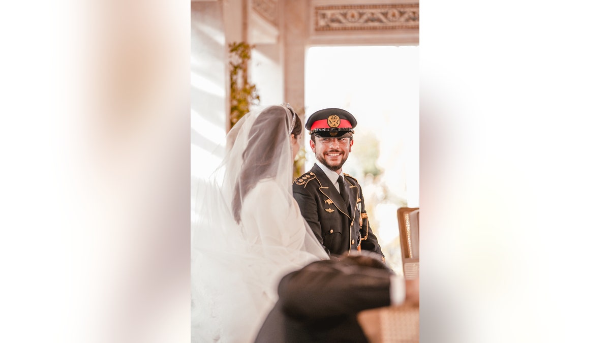 The royal bride and groom of Jordan looking at each other in a bridal gown and military suit