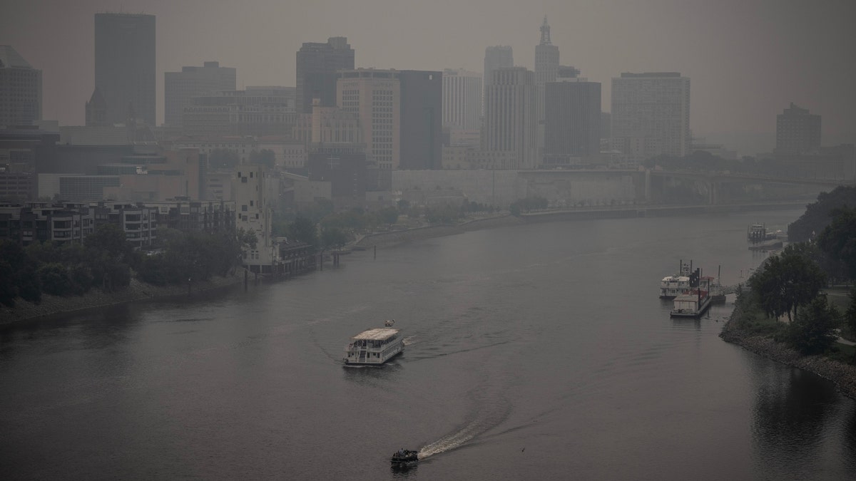 Two boats on the Mississippi River as heavy smoke blankets downtown St. Paul