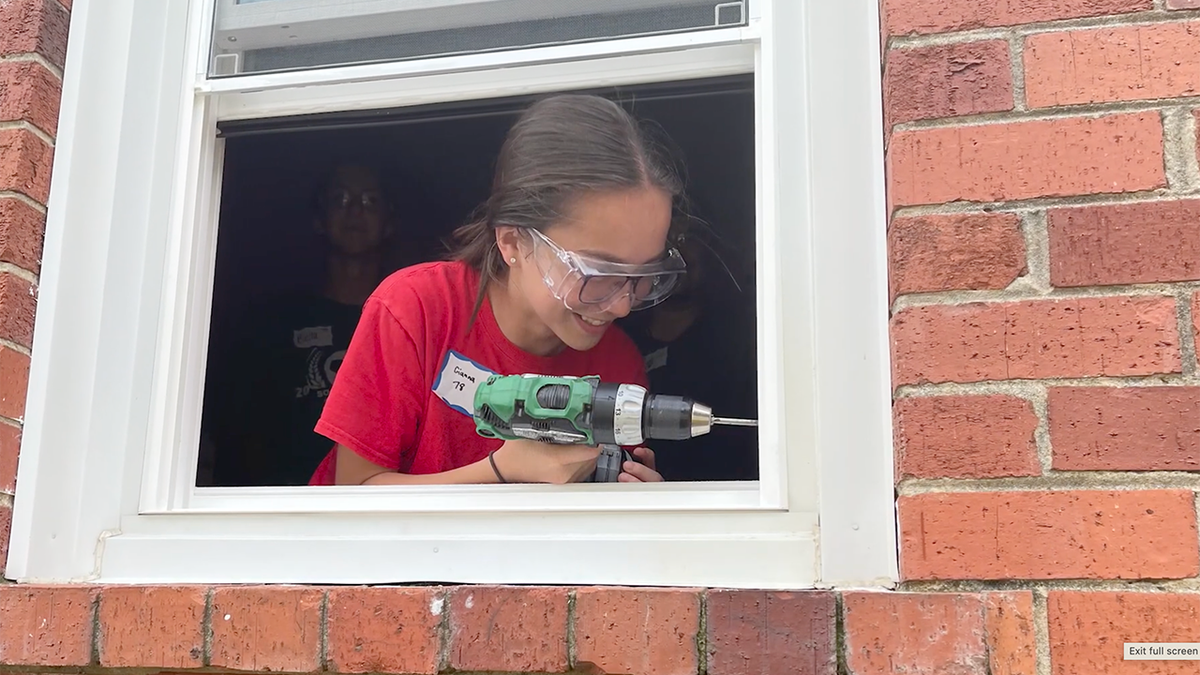 Girl with drill installing window