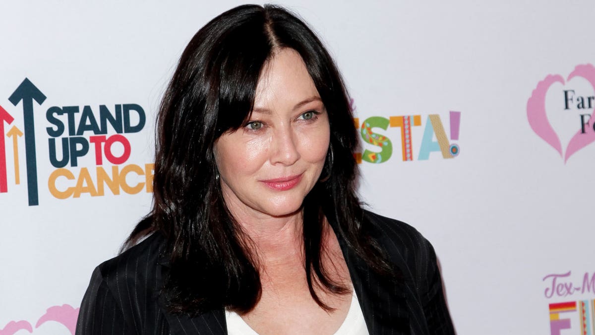 Shannen Doherty in a black blazer and white shirt on the carpet