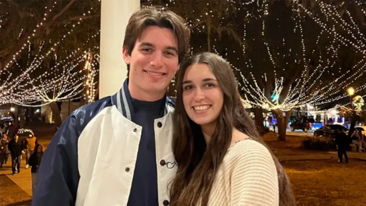 Spencer Ross Pearson and Madison Schemitz pose in front of Christmas lights.