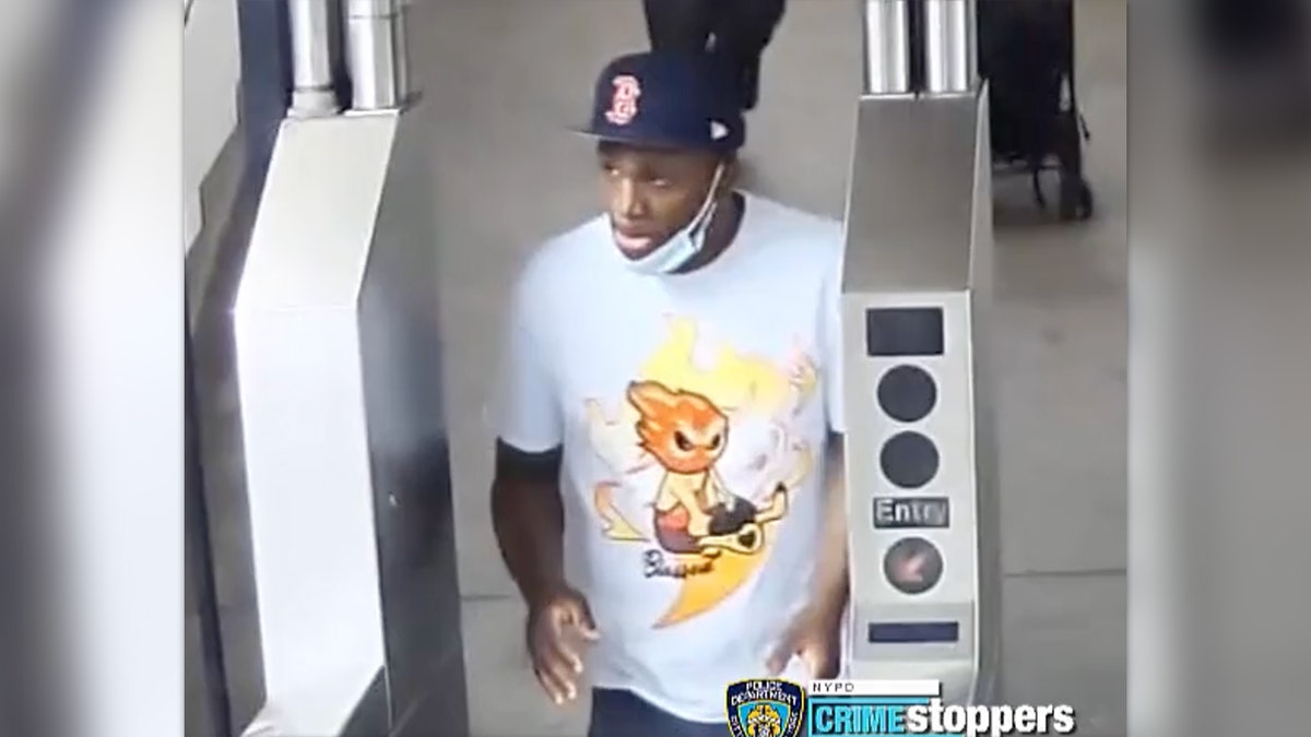 Slashing suspect wears Boston Red Sox hat and white Graphic T standing at NYC subway turnstile
