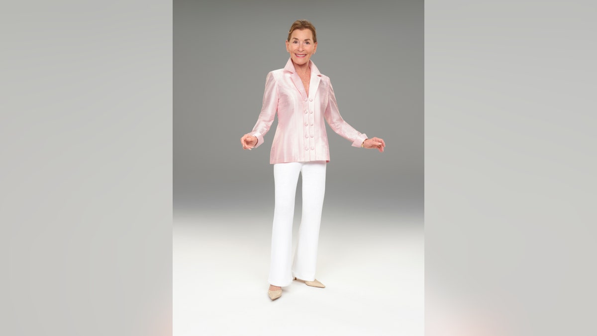 Judge Judy in a pink jacket and white pants
