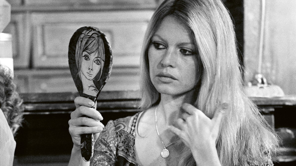 Brigitte Bardot looking somber at a mirror