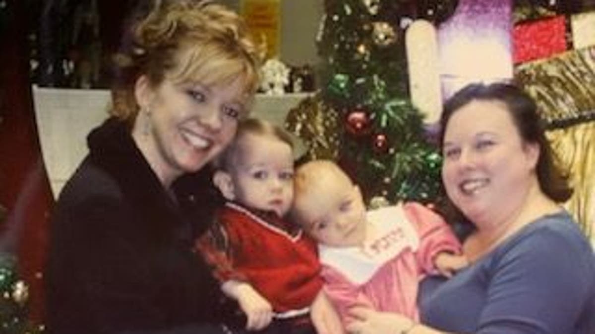 Mom with blonde hair holding baby boy on the left mom with brown hair holding baby girl on the right