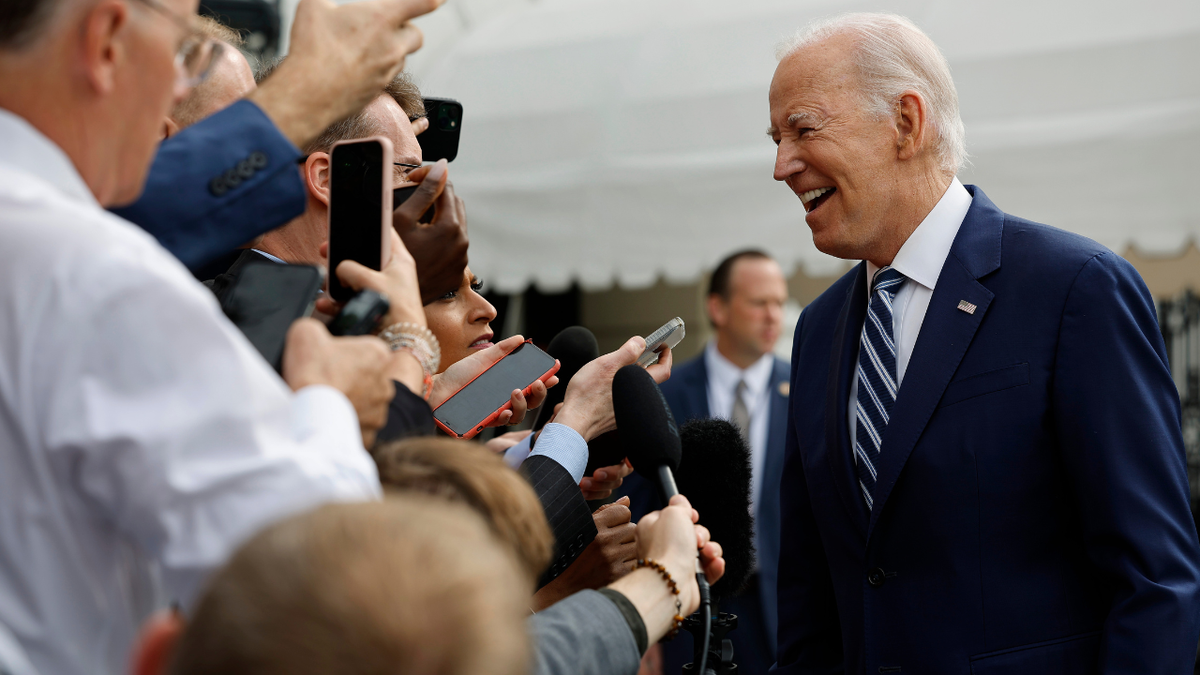 Joe Biden smiling in front of reporters