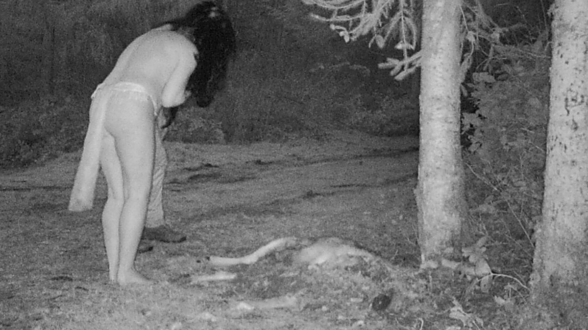 woman and man standing over deer carcass