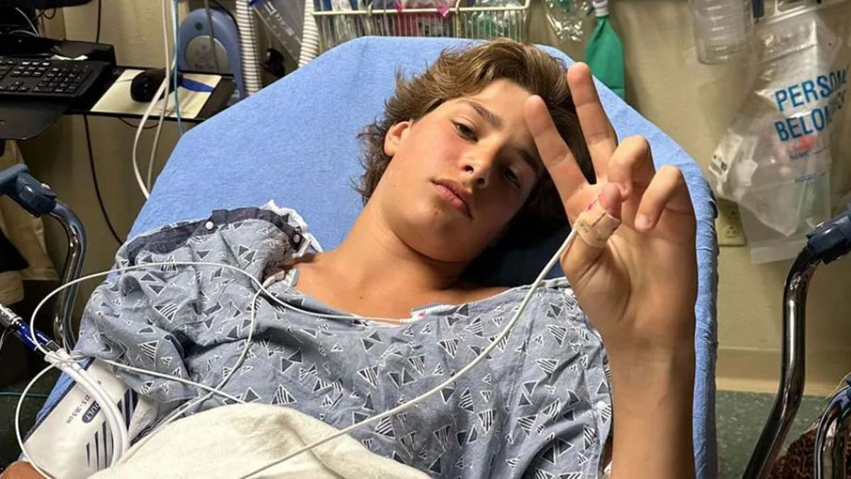 Gabriel Klimis flashing the peace sign from his hospital bed