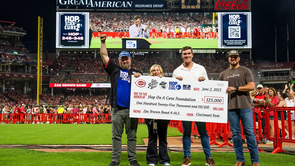 John Driskell Hopkins holds a check for his nonprofit