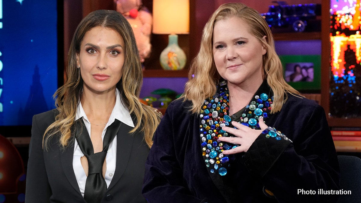 Amy Schumer holds her hand to her heart next to Hilaria Baldwin who wears a black suit
