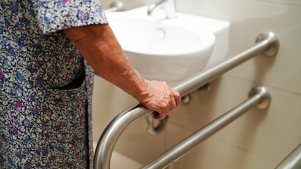 Woman holding onto handrail in bathroom 