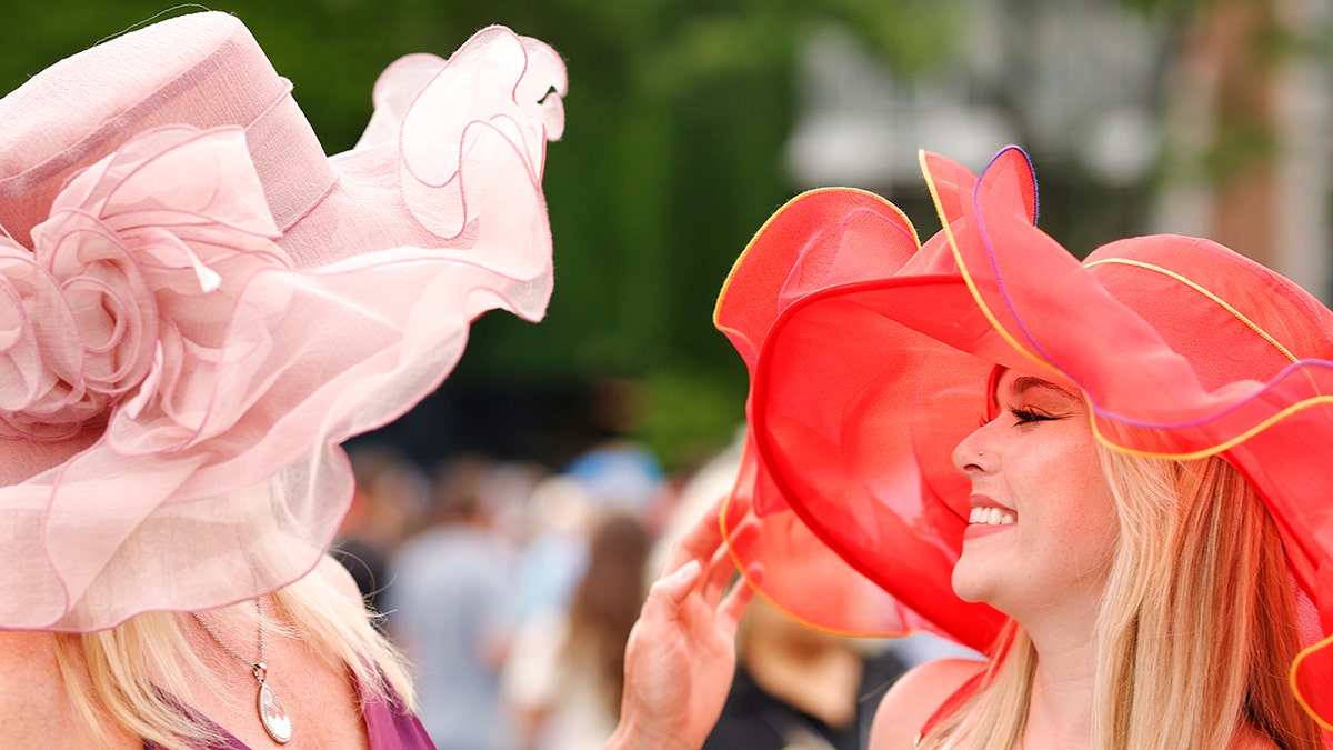 Two spectators wearing extravagant, colorful hats for the Belmont Stakes