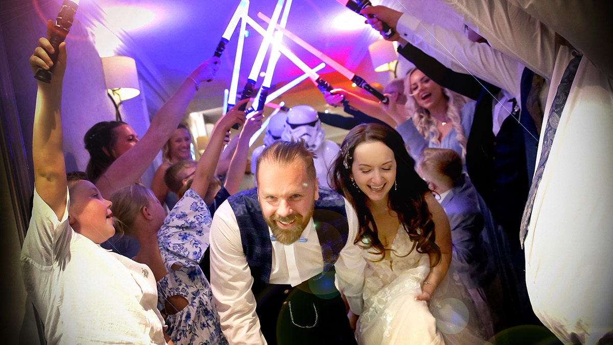 Wedding guests use lightsabers to escort out bride and groom