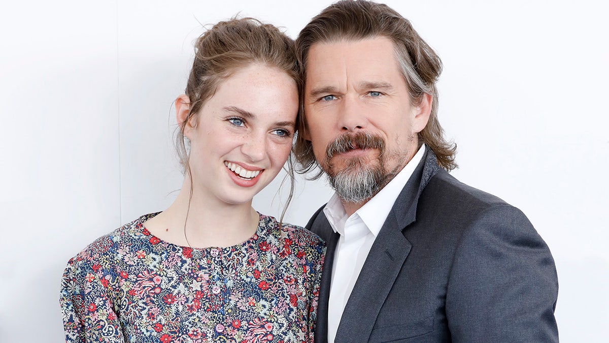 Ethan Hawke, MMaya Hawke in a floral dress rests her head against her father Ethan Hawke's on the carpetaya Thurman-Hawke