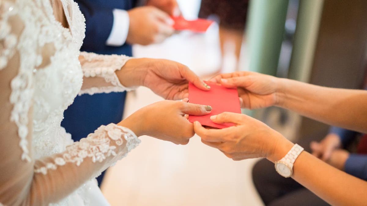 Newlyweds receives money successful reddish envelopes.