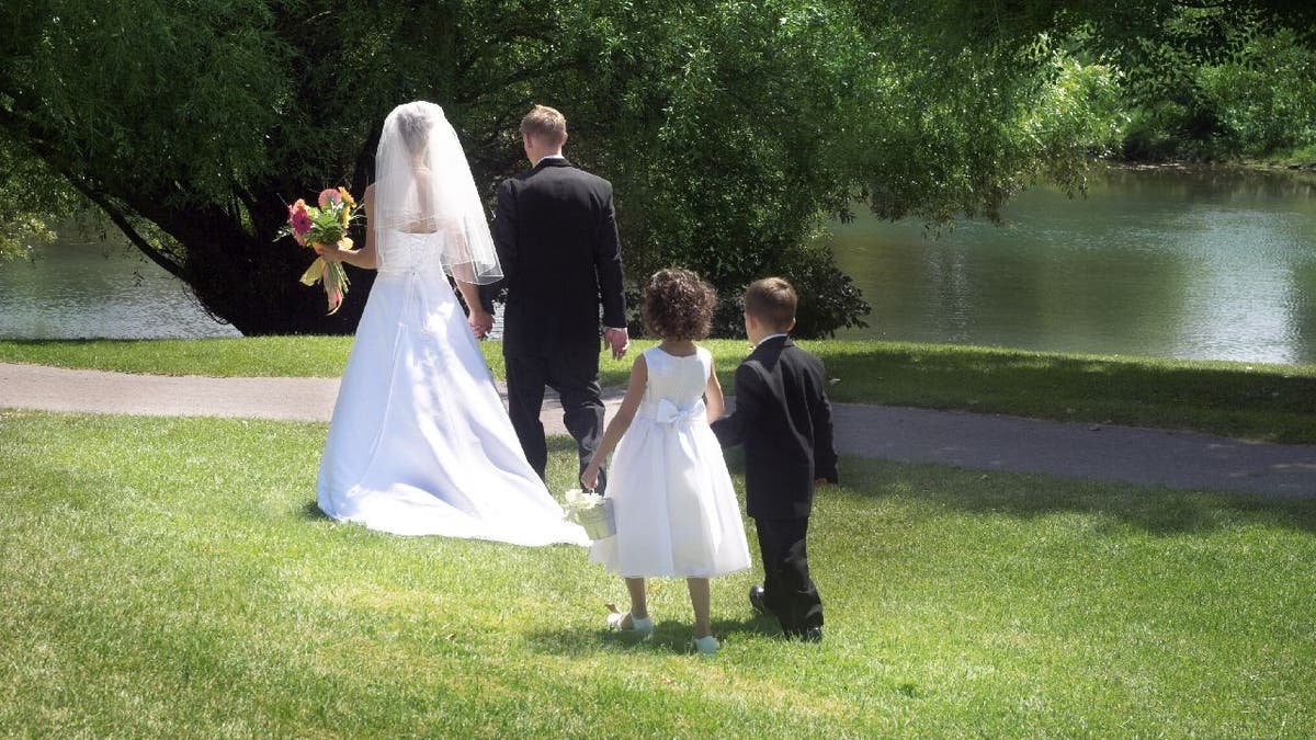 A flower girl and ring bearer follow a bride and groom.
