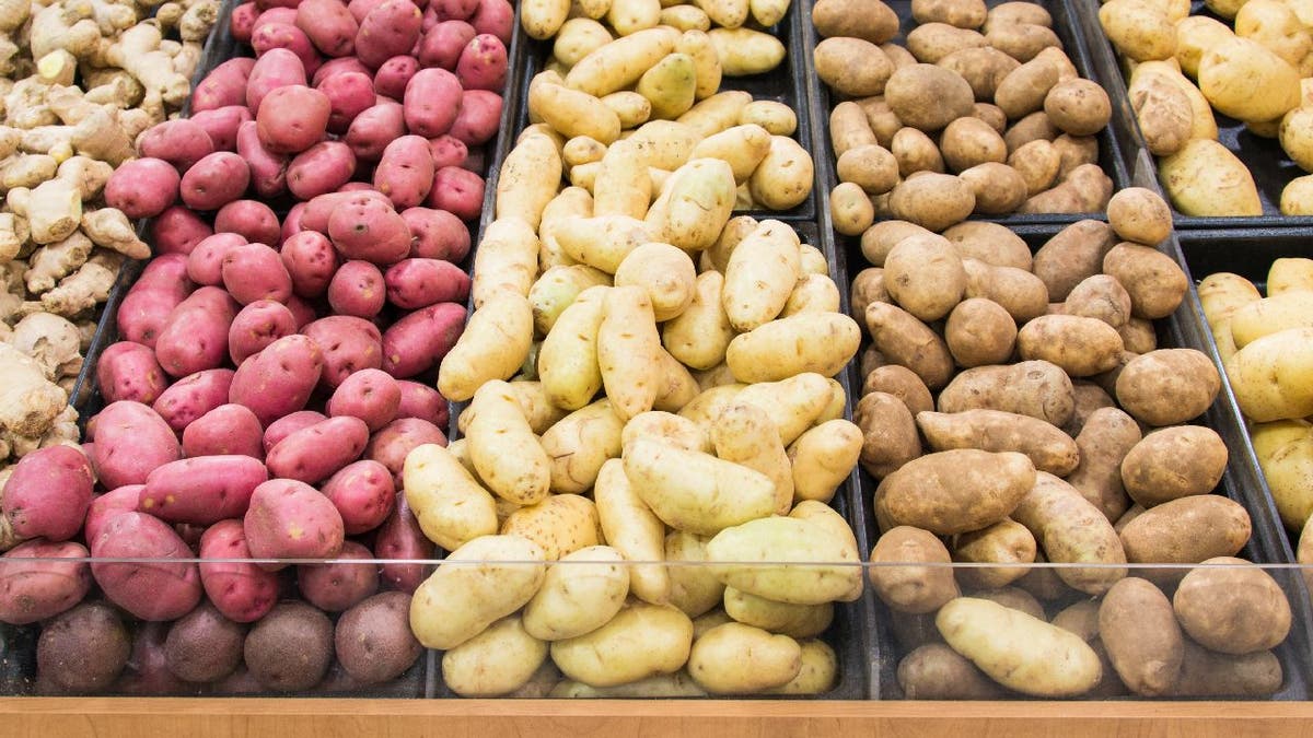 Grocery store displays different colors and varieties of potatoes for people to select.