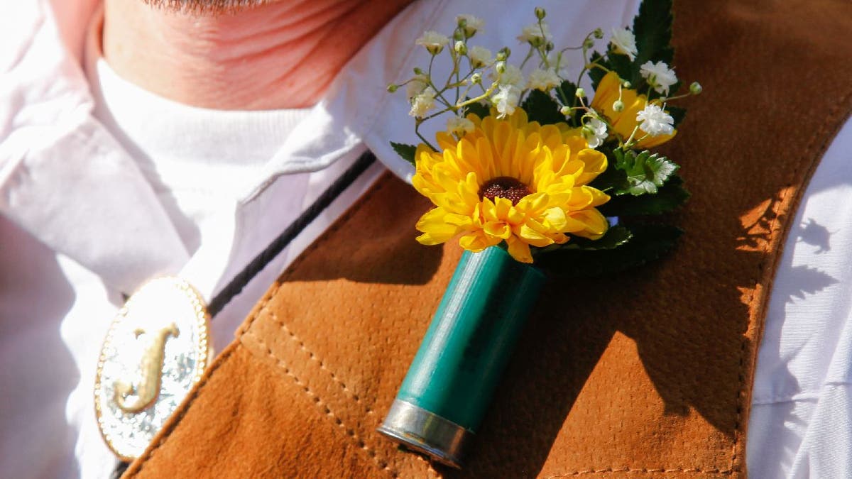 Man wears shotgun boutonniere in what appears to be a cowboy-themed wedding.