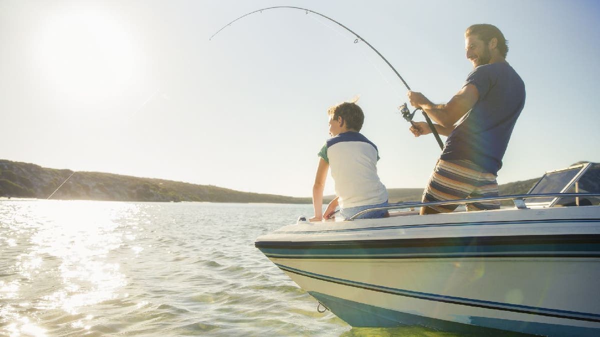 Father and son go fishing on a boat.