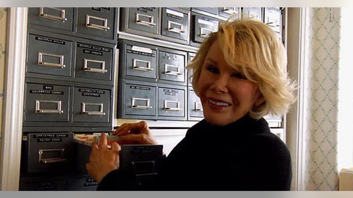 Joan Rivers smiling at her card catalog of jokes