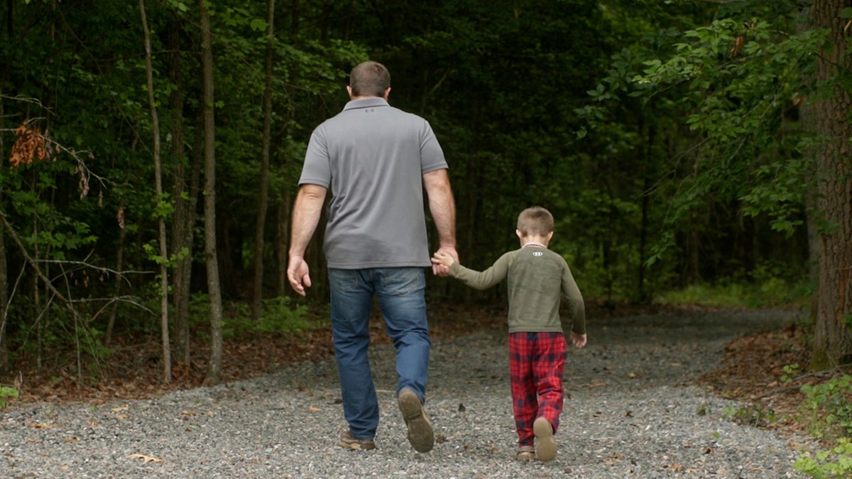 Josh Highlander and his young son walk down a trail outside their Virginia home