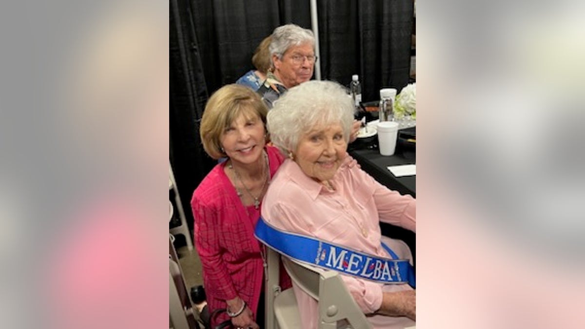 Two Women at a table, one is melba one is Drew Dillard, a man is in the background