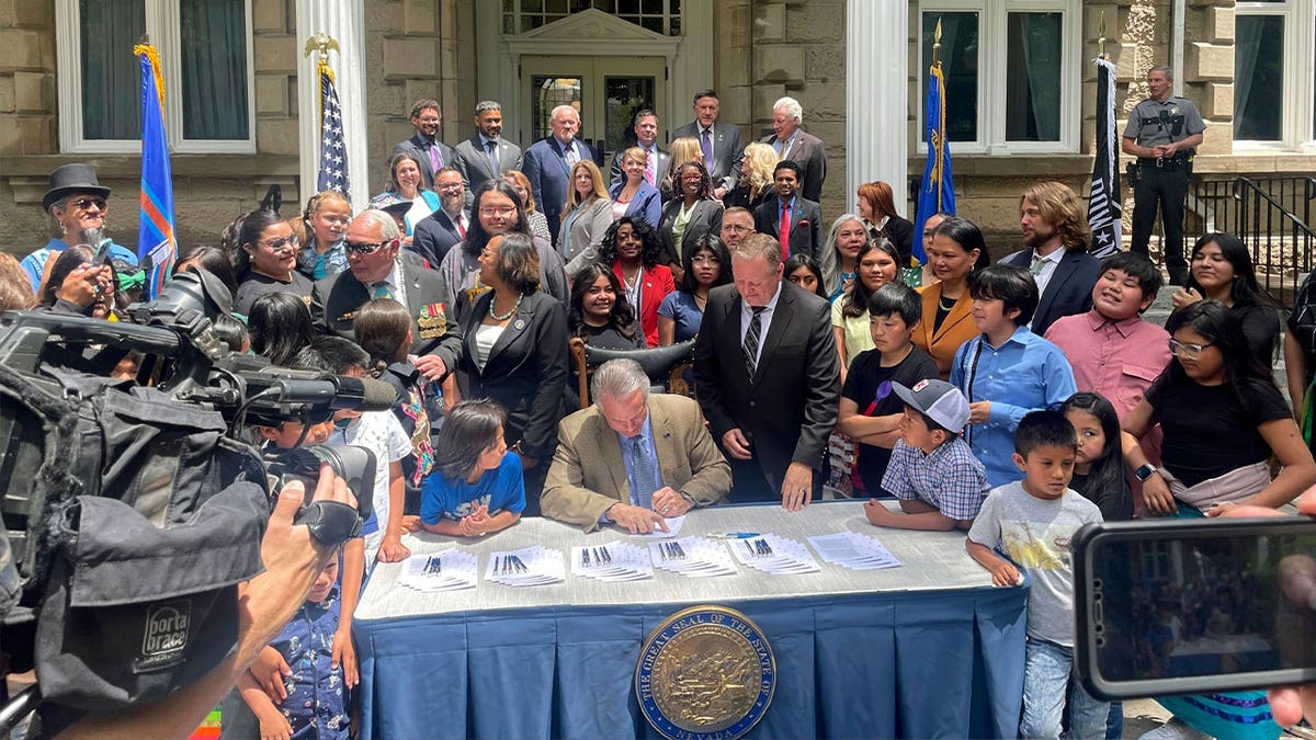 Nevada Gov. Joe Lombardo signs a bill to provide more rural and tribal school funding, flanked by dozens of legislators, tribal members, and students outside the state Capitol on June 13, 2023, in Carson City.