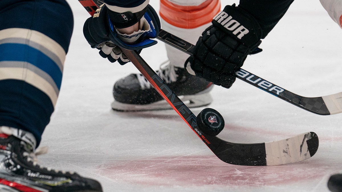 Players fighting for puck on hockey rink