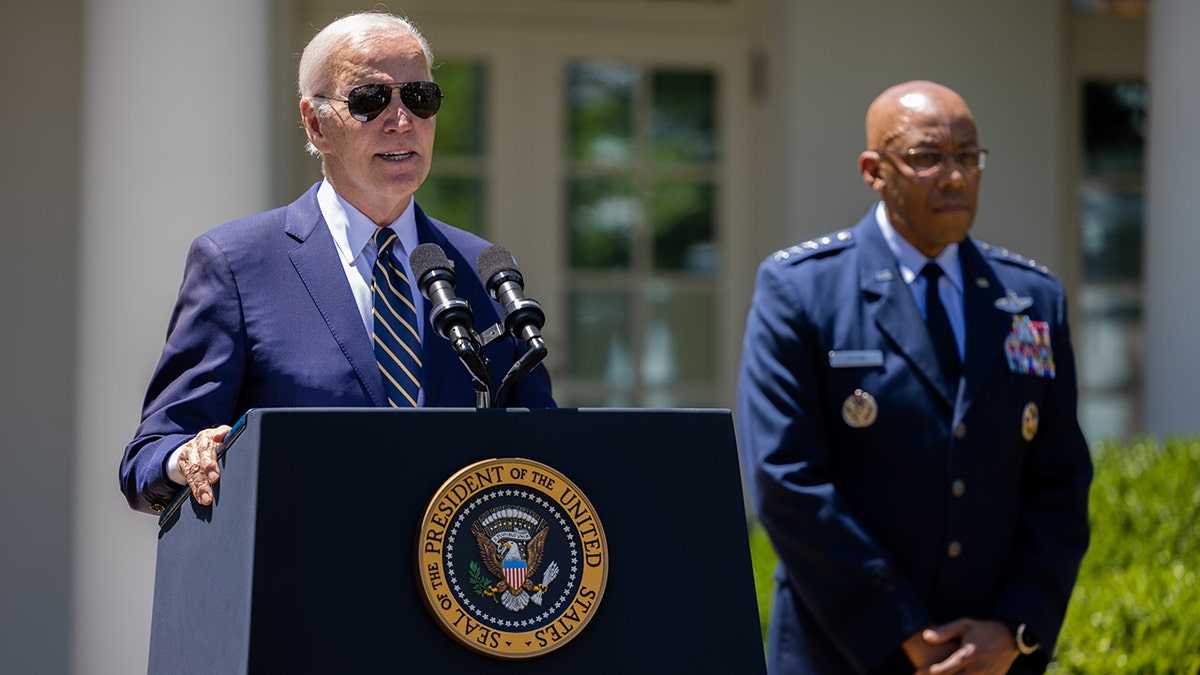 President Biden speaks from a podium at the White House as Air Force Gen. Charles Q. Brown Jr. stands beside him