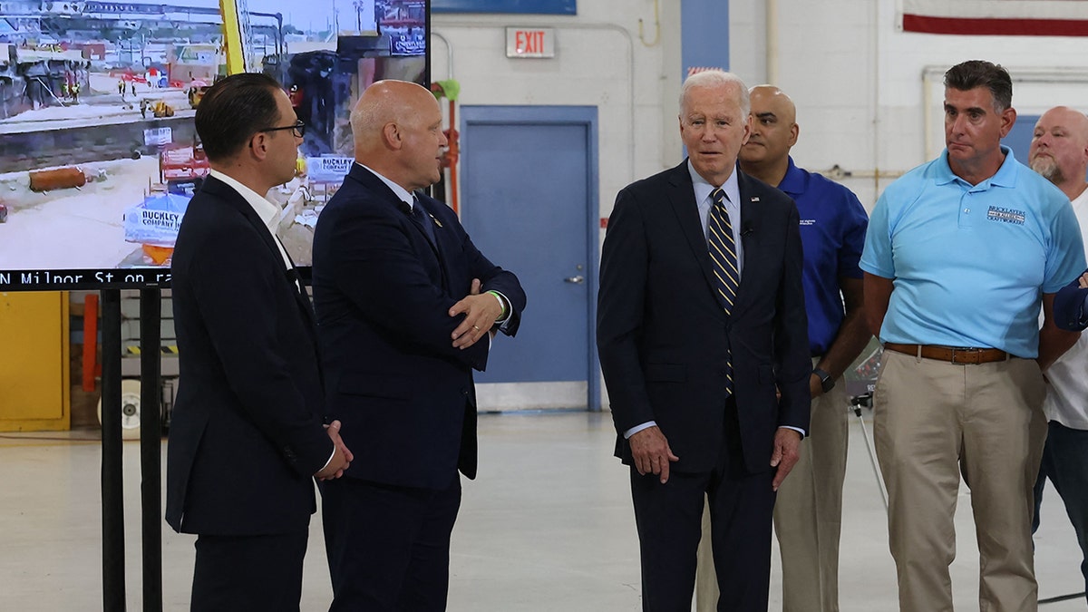 President Biden is surrounded by Pennsylvania officials as he watches live footage of I-95 construction