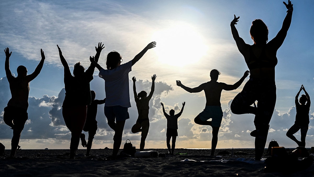 A crowd of people doing yoga at the beach