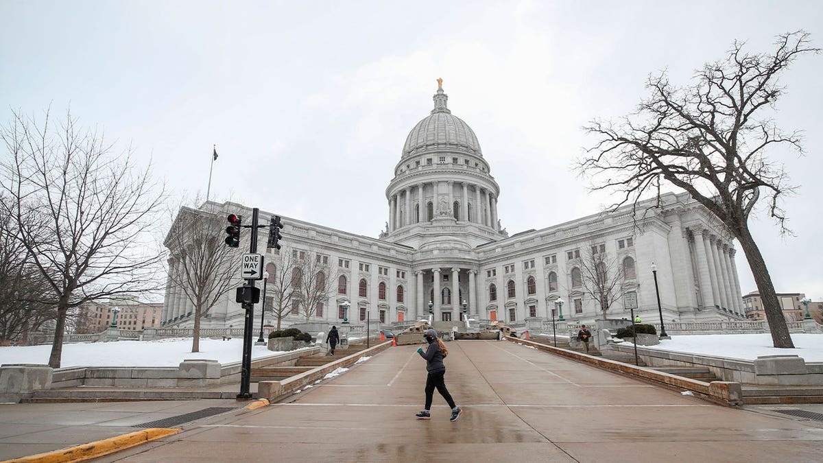 A woman jogs in front of the state Capitol in Madison, Wisconsin, on Jan. 17, 2021. The state Assembly is slated to approve bills aimed at improving the system of issuing professional licenses following a delay caused by the pandemic. 