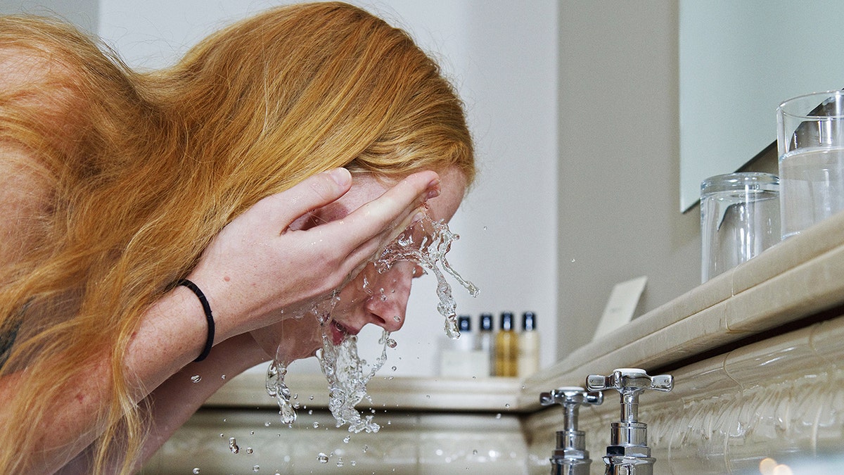 A woman washing her face in the sink