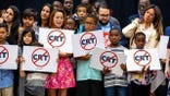 Schoolchildren hold signs against critical race theory, a school of thought that generally focuses on how power structures and institutions impact racial minorities.