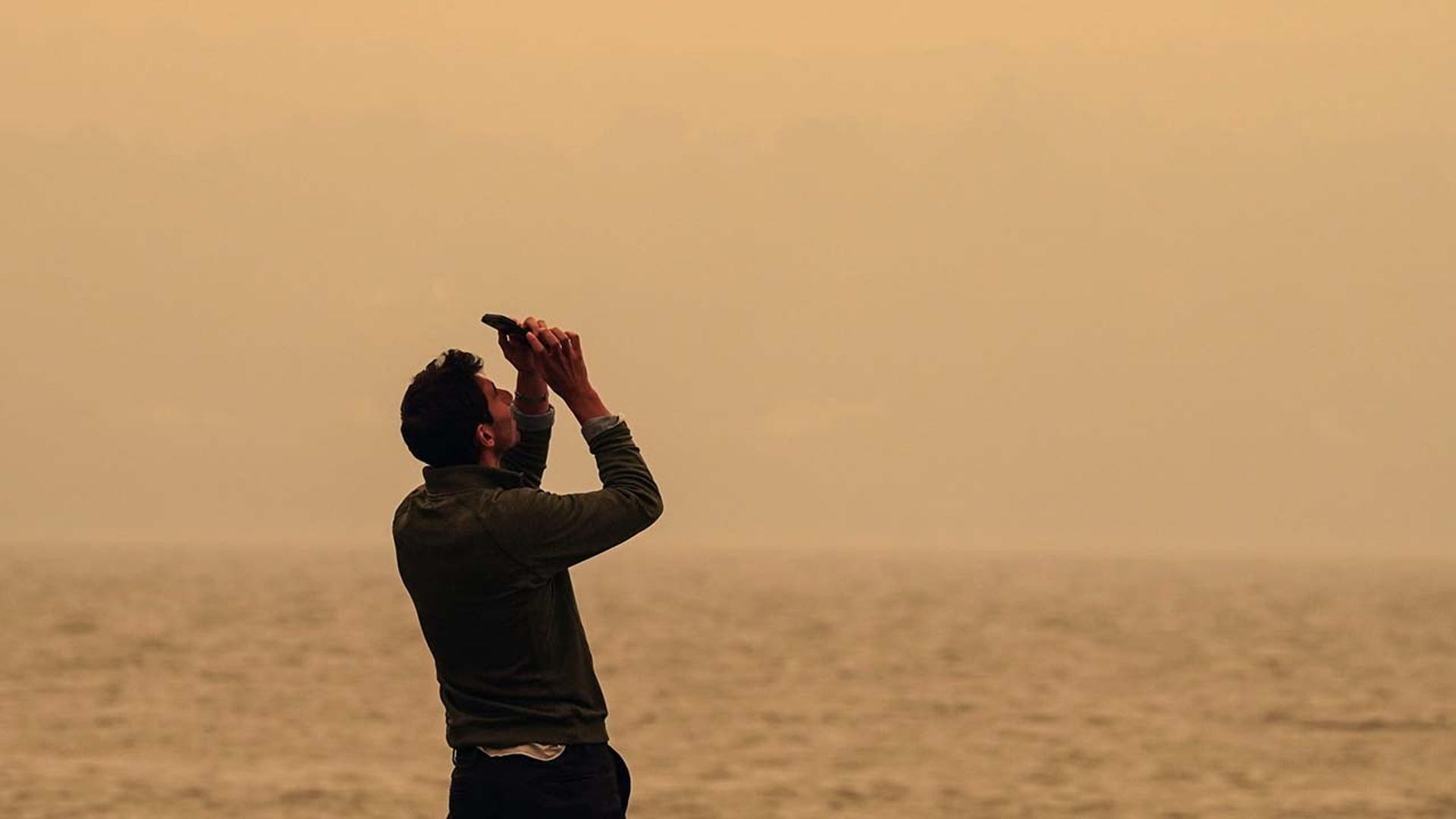 A man takes a photo of the sky.