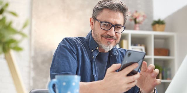 man smiling at his smartphone